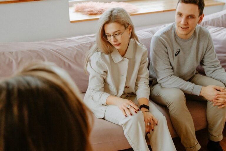 A couple in a counseling session with a therapist in a cozy, modern room.