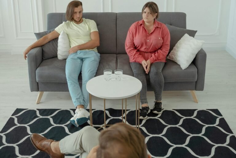 A couple sitting on a sofa during a therapy session with a professional therapist.